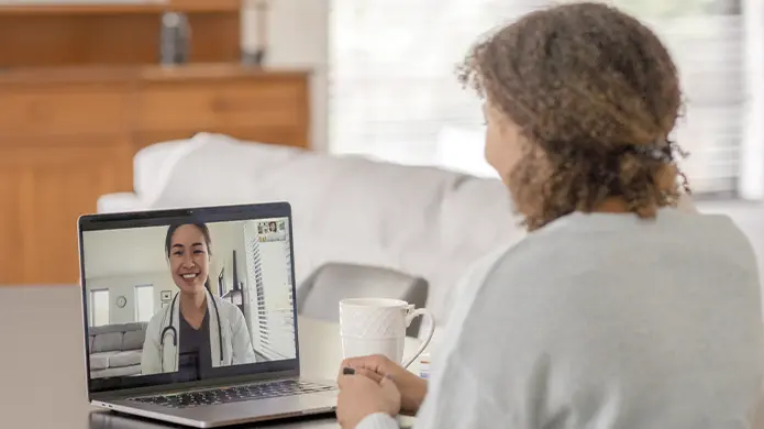 Une personne discute avec une prestataire de soins de santé sur son ordinateur portable.