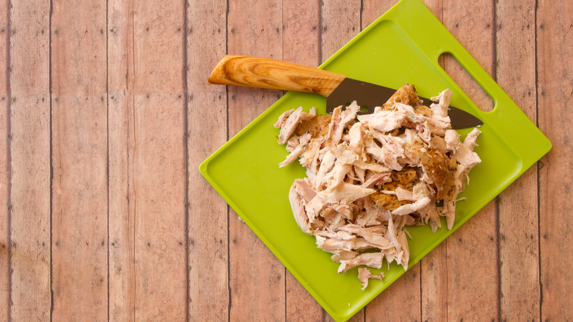 Poulet en morceaux et couteau sur une planche à découper verte en plastique