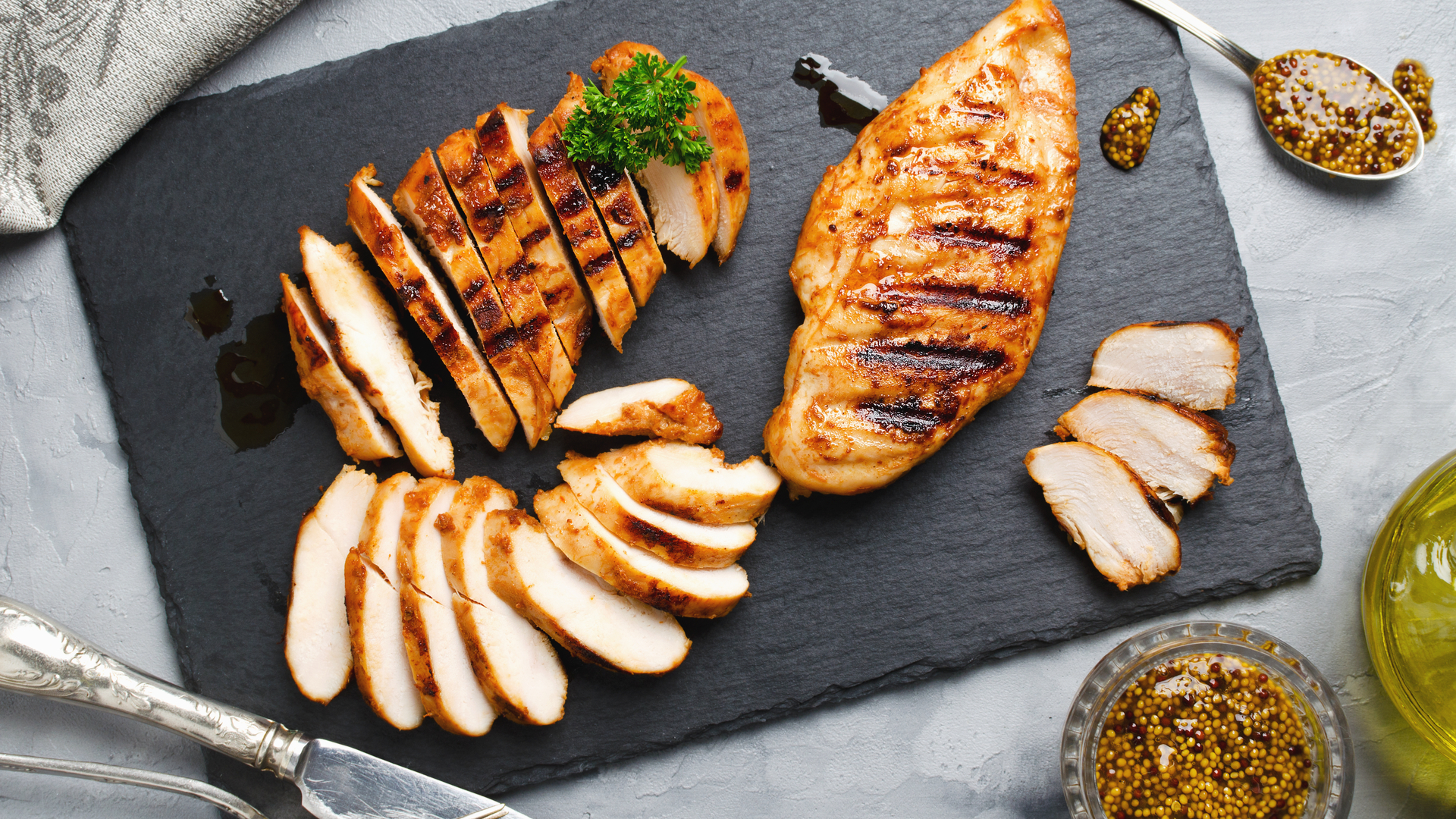Grilled chicken cut into slices on a slate