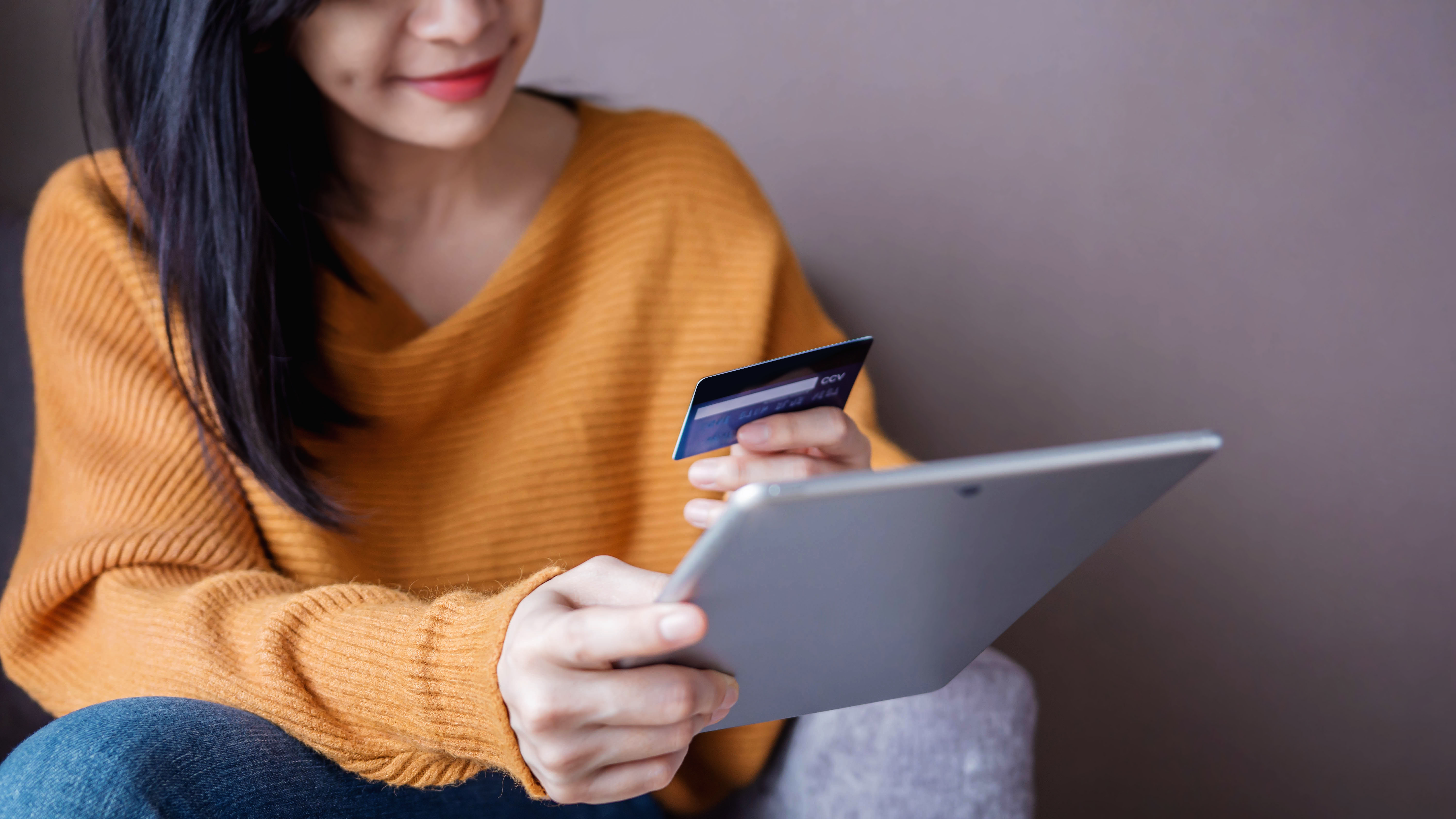 Femme heureuse utilisant une carte de crédit et une tablette pour faire des achats en ligne