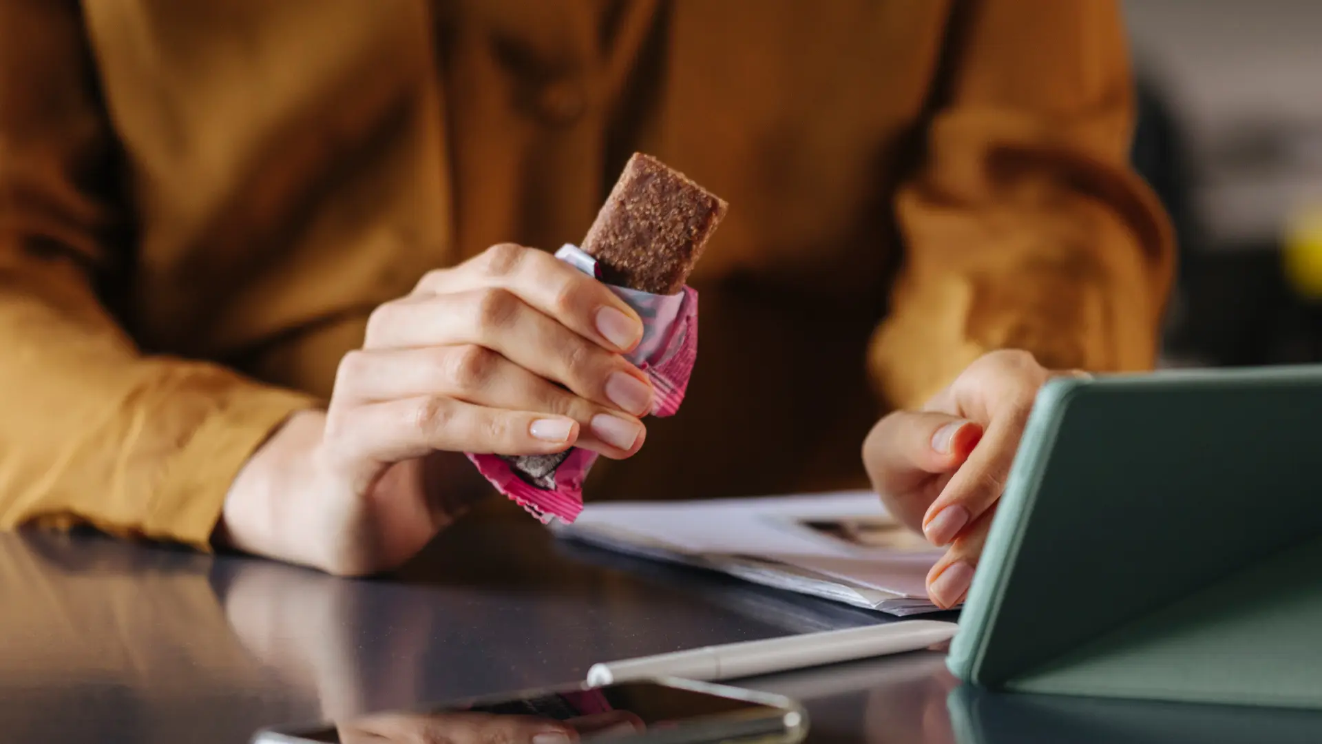 Une femme tient une barre protéinée à une table.