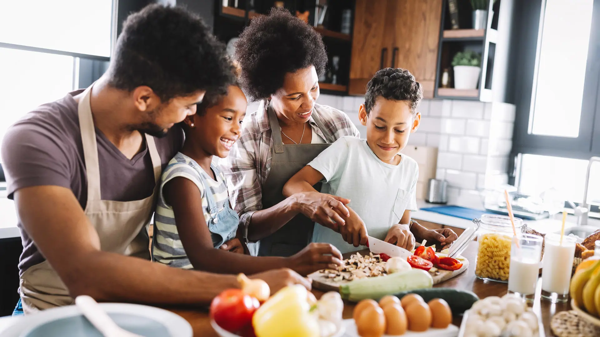 Deux adultes et deux enfants préparent un plat ensemble dans une cuisine.