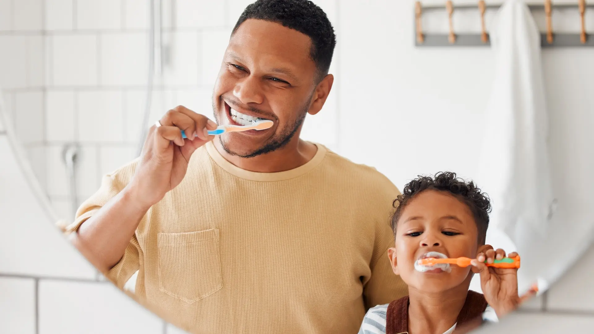 Un homme et sa fille se brossent les dents devant un miroir.