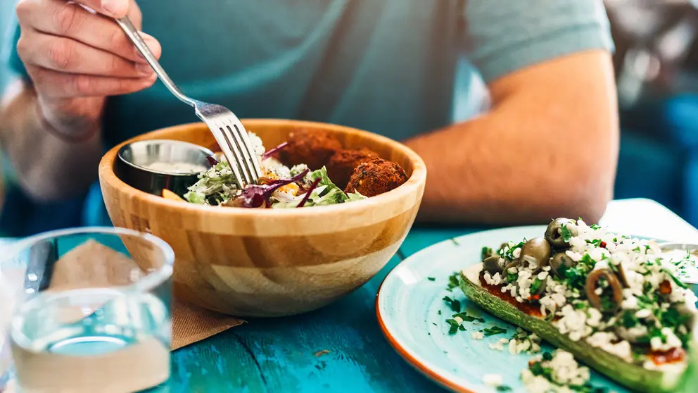 Un homme mange une salade dans un bol