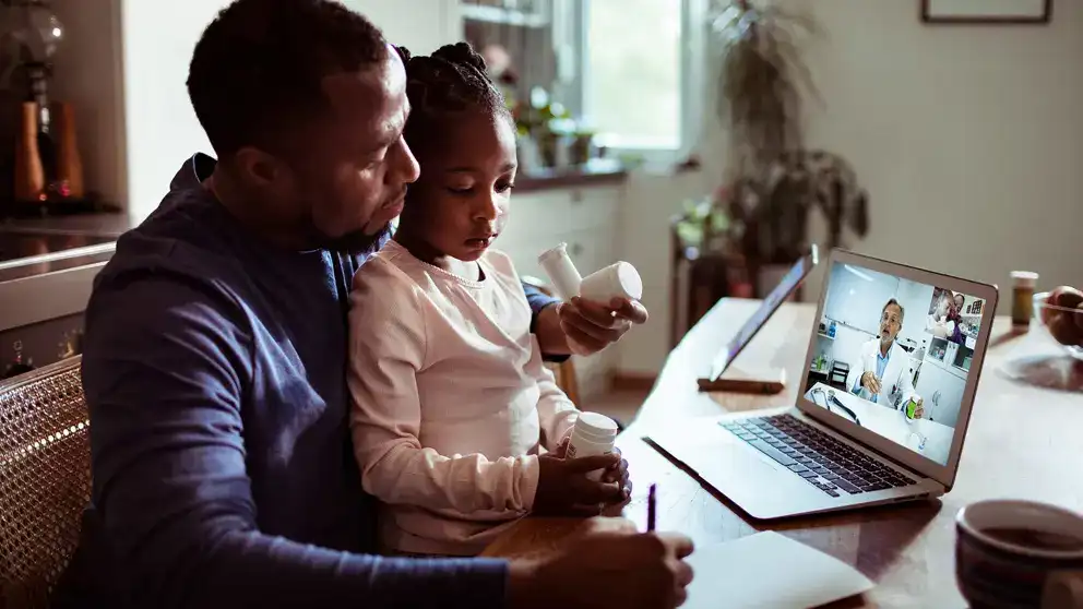 Un père et sa fille assistent à un rendez-vous médical virtuel.