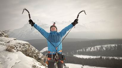 Leo Namen raises his arms to celebrate reaching a mountain summit. 