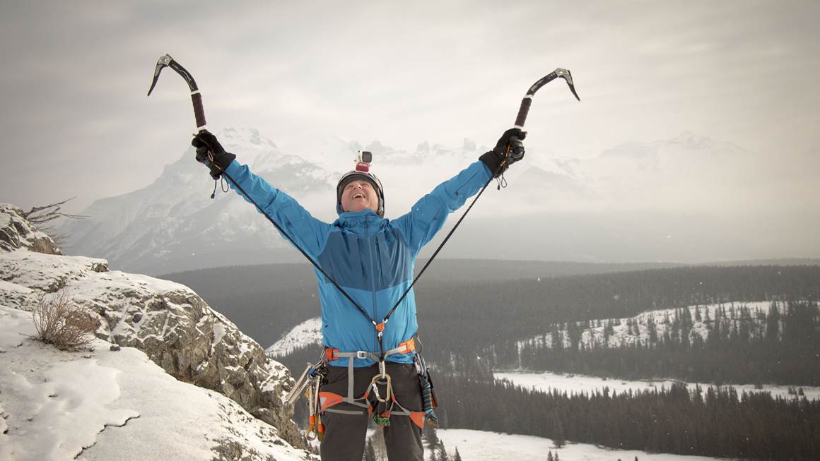 Leo Namen raises his arms to celebrate reaching a mountain summit. 