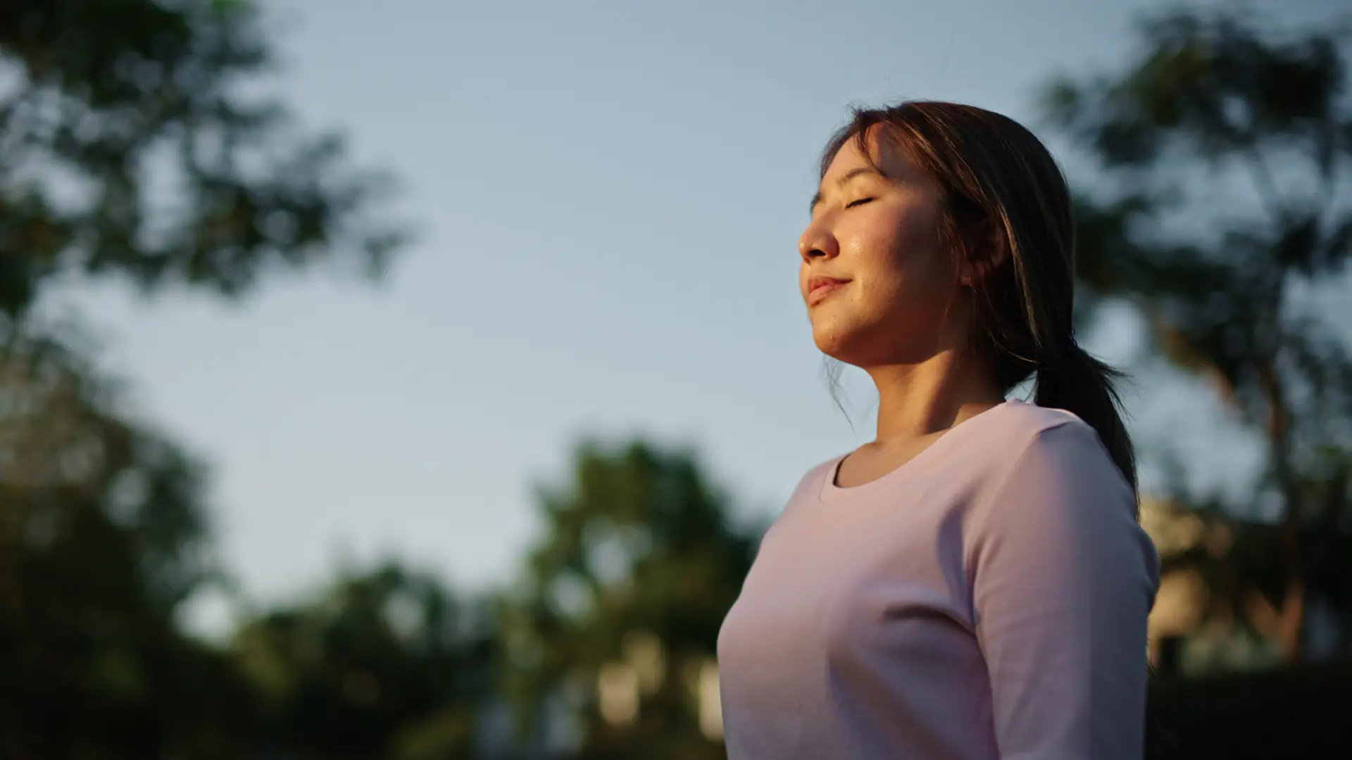 Une personne avec les yeux fermés se tenant debout à l’extérieur