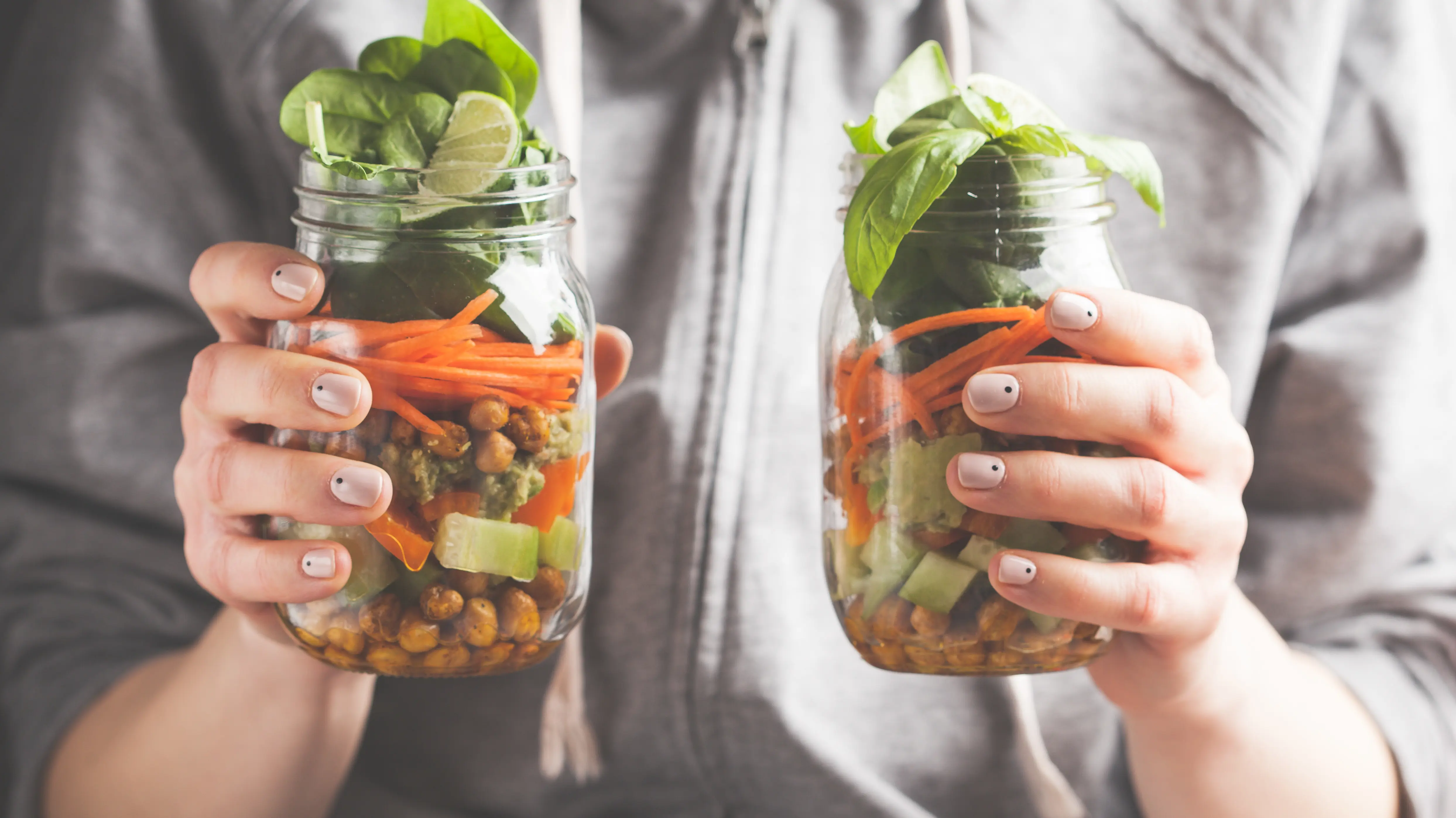 Une femme tient deux salades en pot.