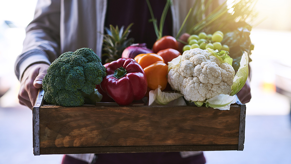 Une femme tenant une boîte en bois avec des légumes