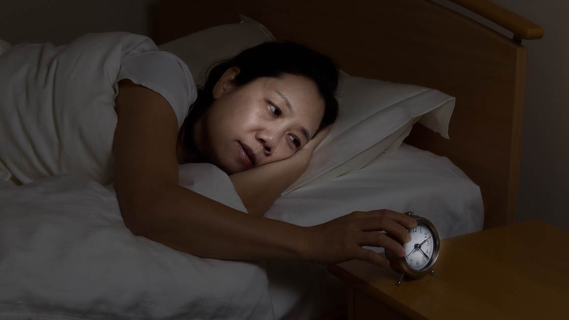 Une femme avec insomnia touche un réveil