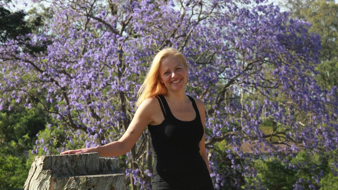 Annie Richard se tenant debout devant un arbre à fleurs pourpres
