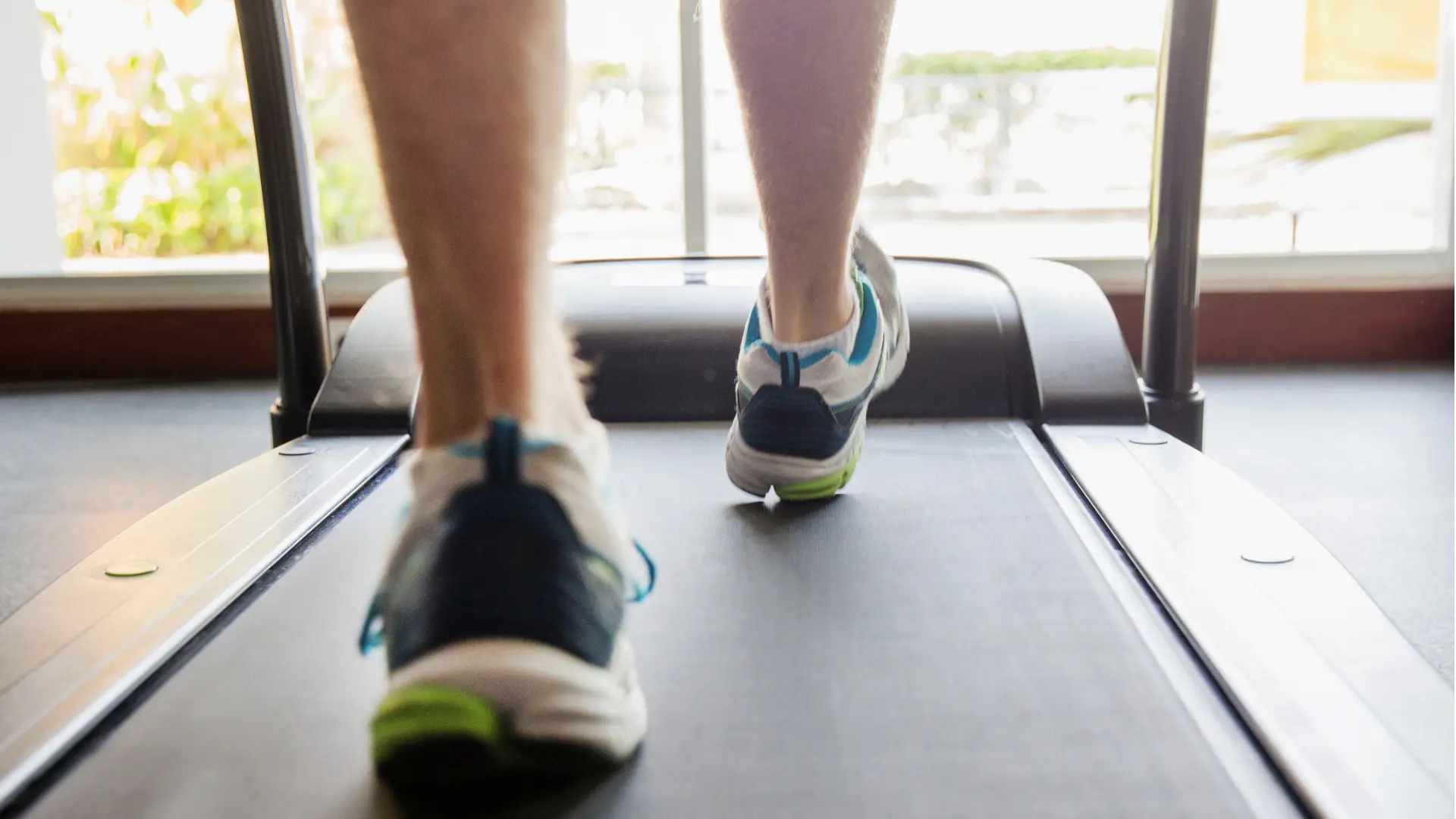 Gros plan des pieds d’un homme qui court sur un tapis roulant.