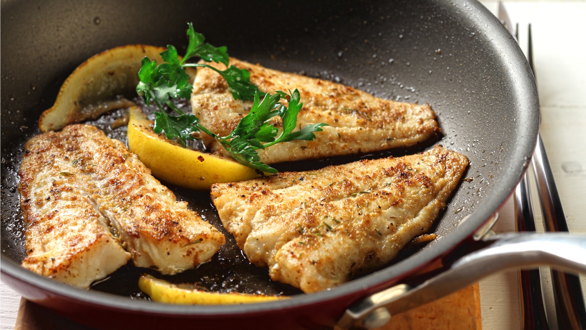 Trois morceaux de poisson cuit au poivre avec du citron et des herbes