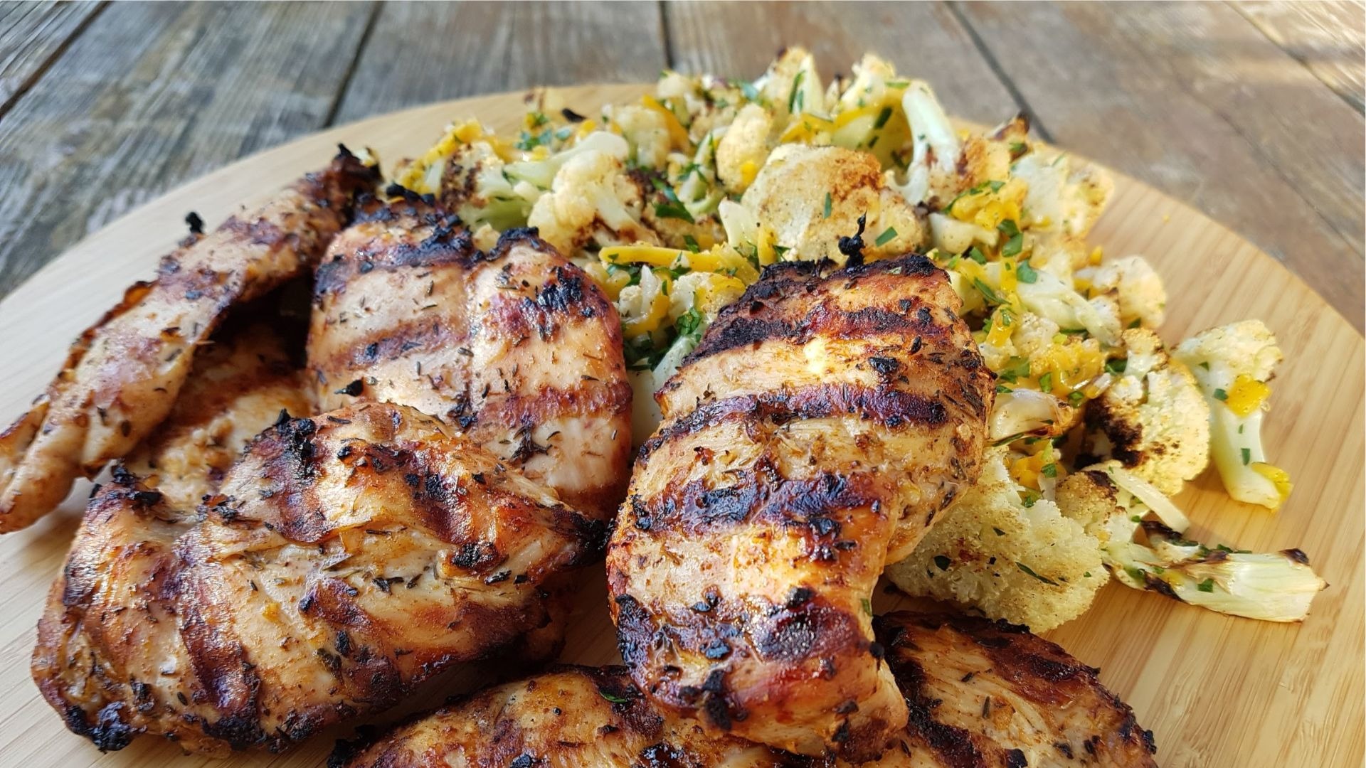 Poulet et bouquets de chou-fleur grillés sur une planche de bois