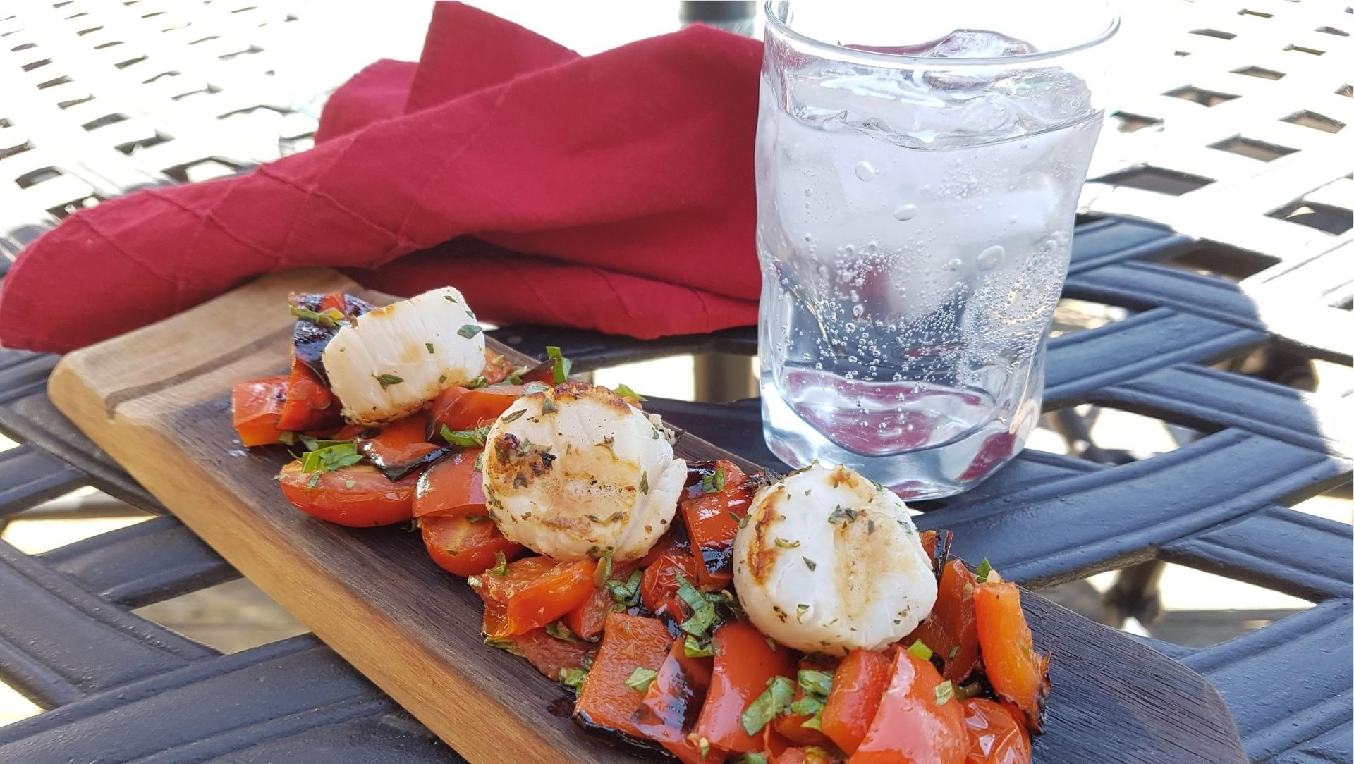 Pétoncles grillés aux tomates rôties sur une planche de bois