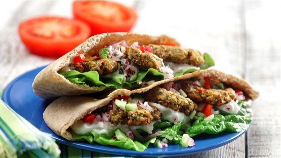 Pain pita rempli de falafel, de laitue, de tzatziki, de tomates, d'oignon et concombre