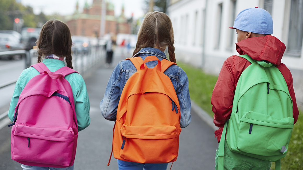  Trois enfants avec des sacs à dos marchent pour aller à l’école.