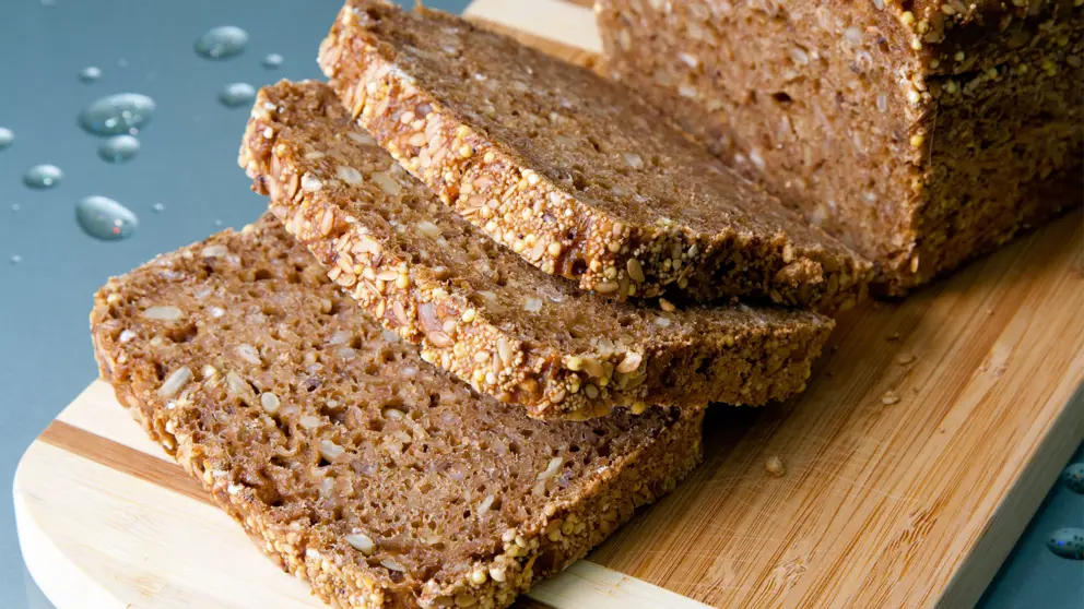 Miche de pain de grains entiers et les tranches sur une planche à découper en bois