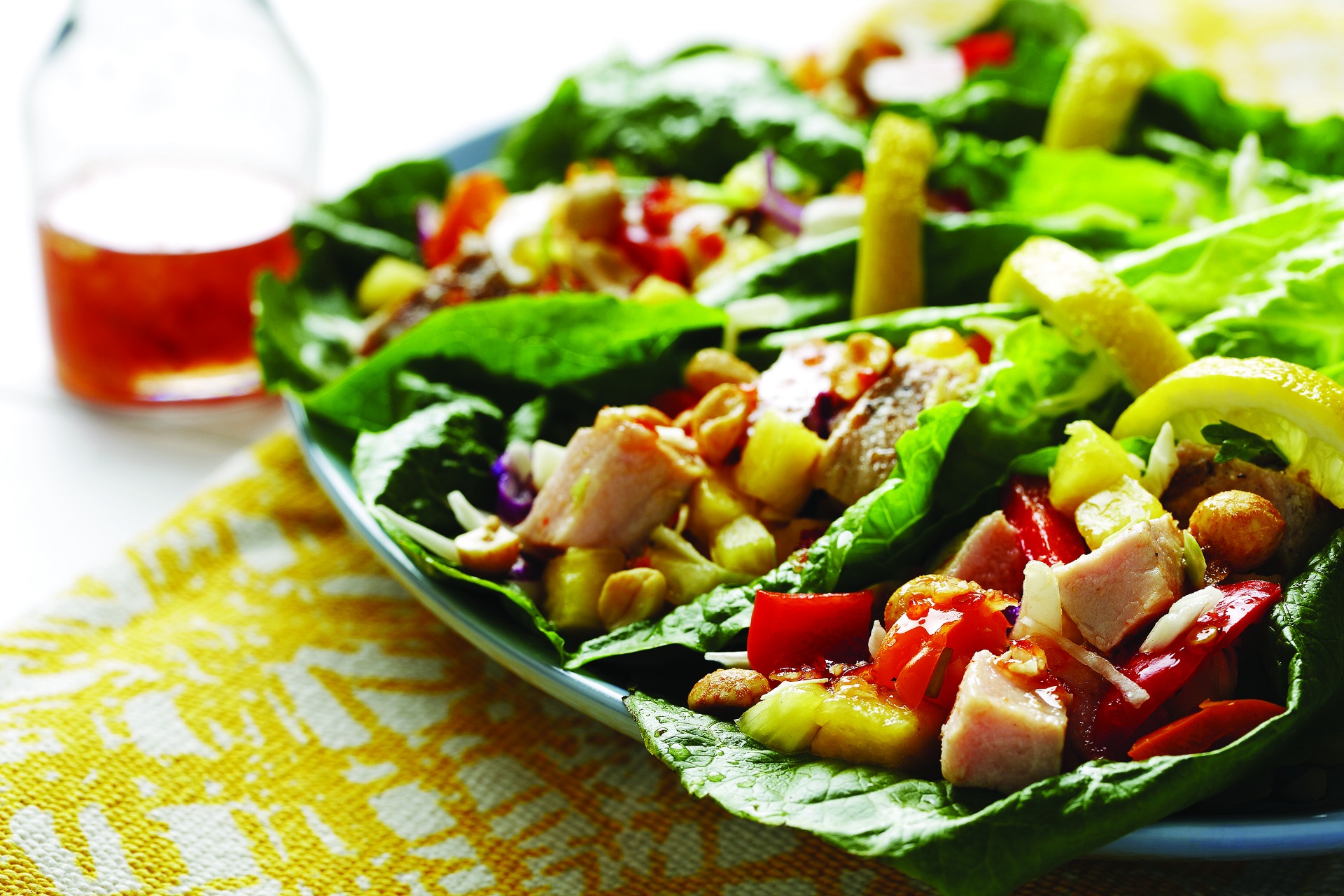 Poulet haché, poivrons rouges, ananas et arachides hachés sur une feuille de laitue