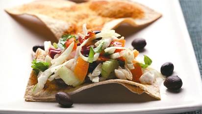 Salade de chou avec tortillas de blé entier triangulaires sur une assiette blanche.