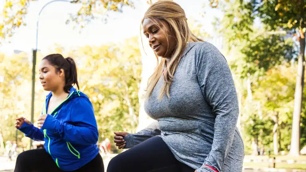 Deux femmes qui font des mouvements brusques sur un banc de parc en plein air
