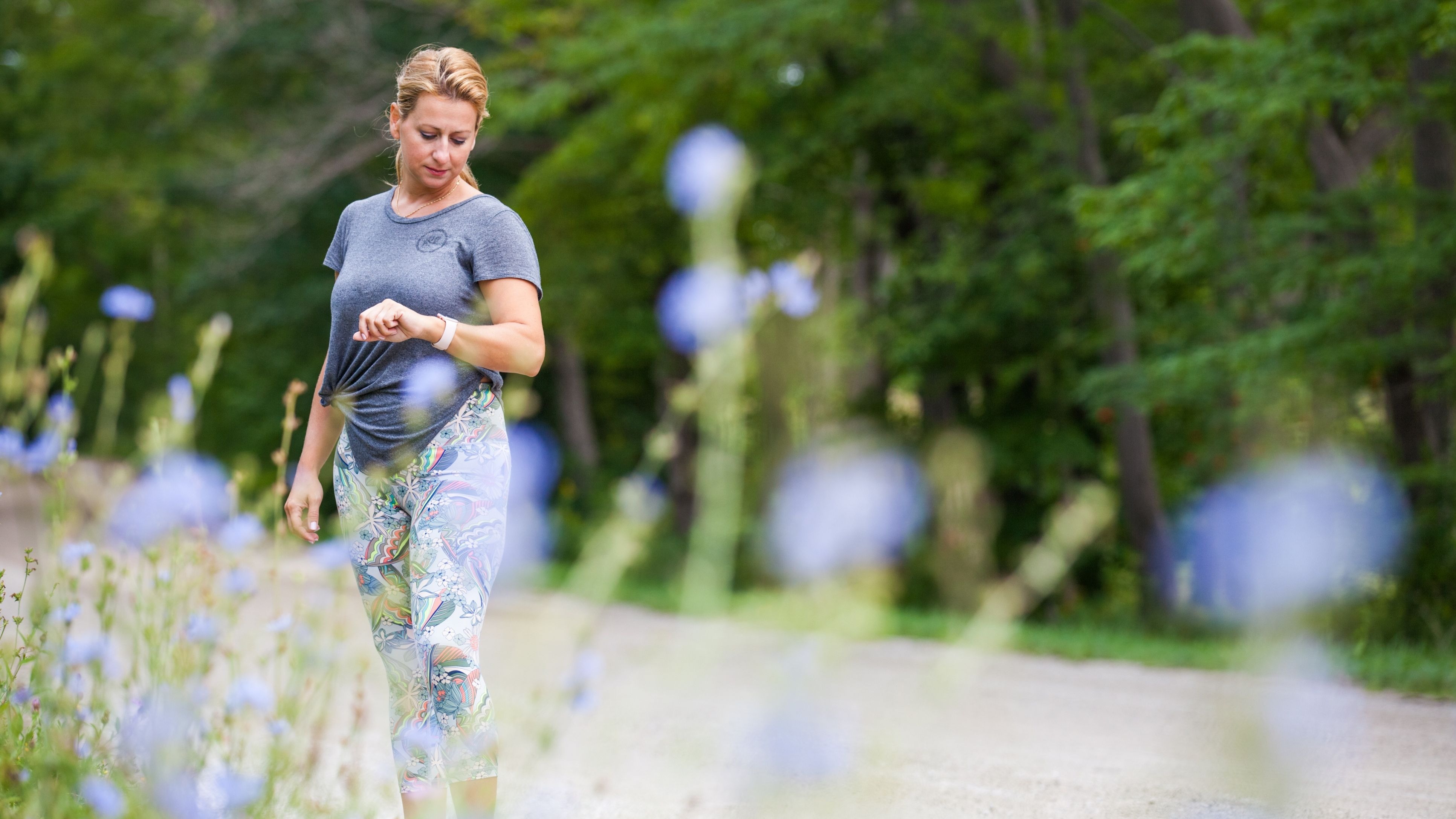 Une femme faisant de l'exerice dehors regarde son moniteur d'activité physique