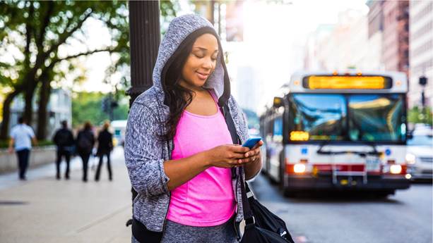 young woman waiting for bus checking her cell phone