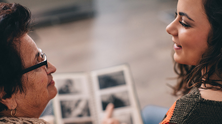 Une grand-mère et sa petite-fille qui parlent en regardant un album photo.