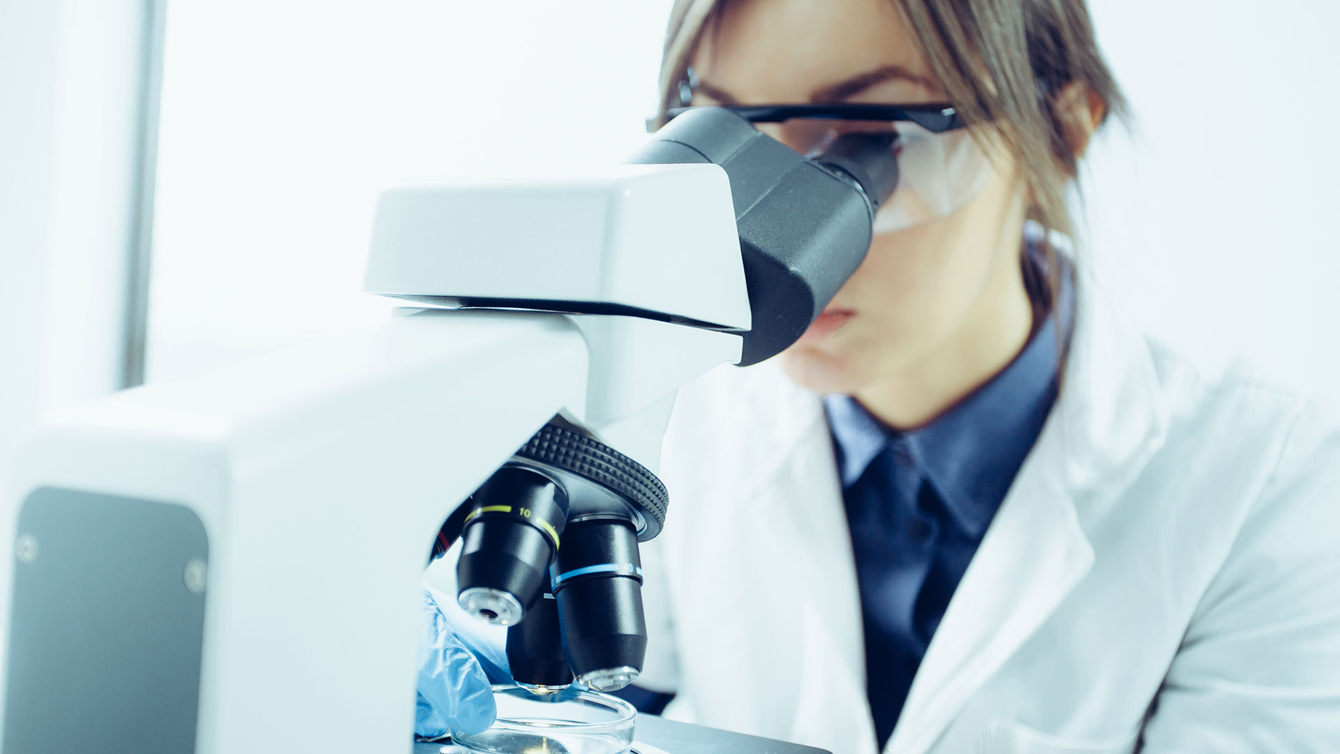 Jeune scientifique regardant à travers un microscope dans un laboratoire