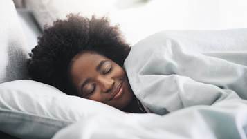 Une femme souriante dort sur un lit.