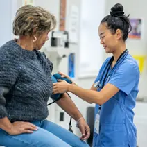 Une infirmière vérifie la pression artérielle d’une patiente.
