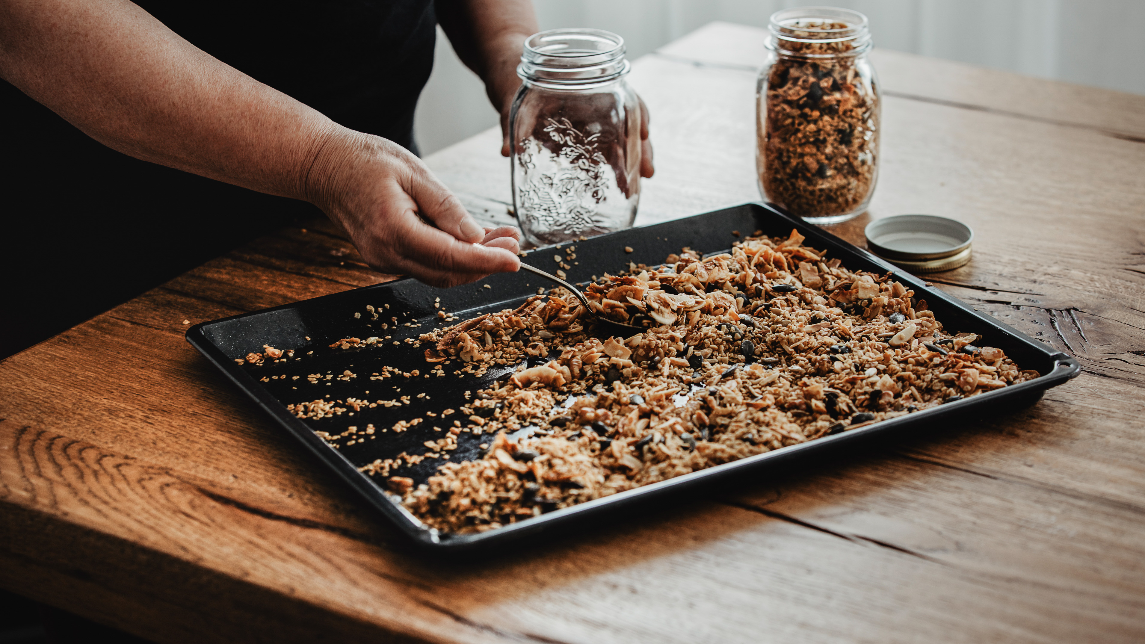 Une femme remplissant des pots de granola maison.