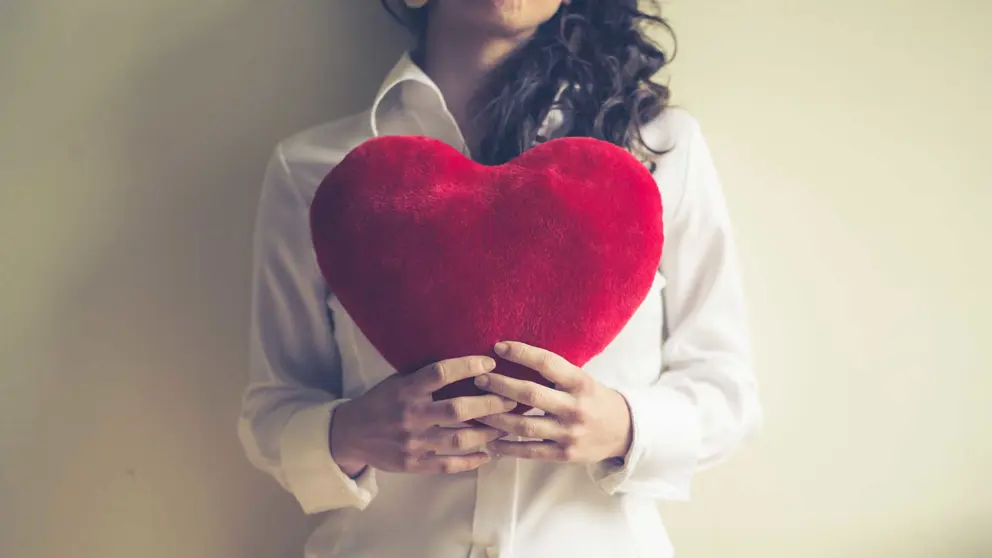 Femme, tenant coeur en peluche rouge devant sa poitrine