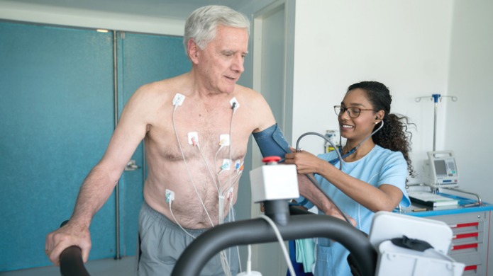 Une infirmière mesurant la pression artérielle d’un patient sur un tapis roulant.