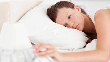 femme rousse couché dans le lit d'éteindre un réveil dans sa chambre