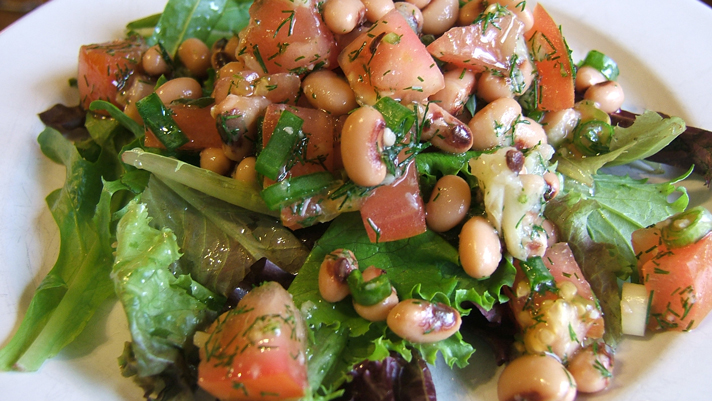 Salade de doliques et d’ail rôti sur une assiette blanche
