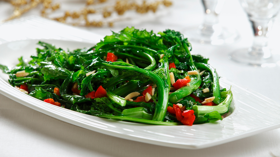 Rapini sauté servi sur une assiette blanche, sur une nappe blanche