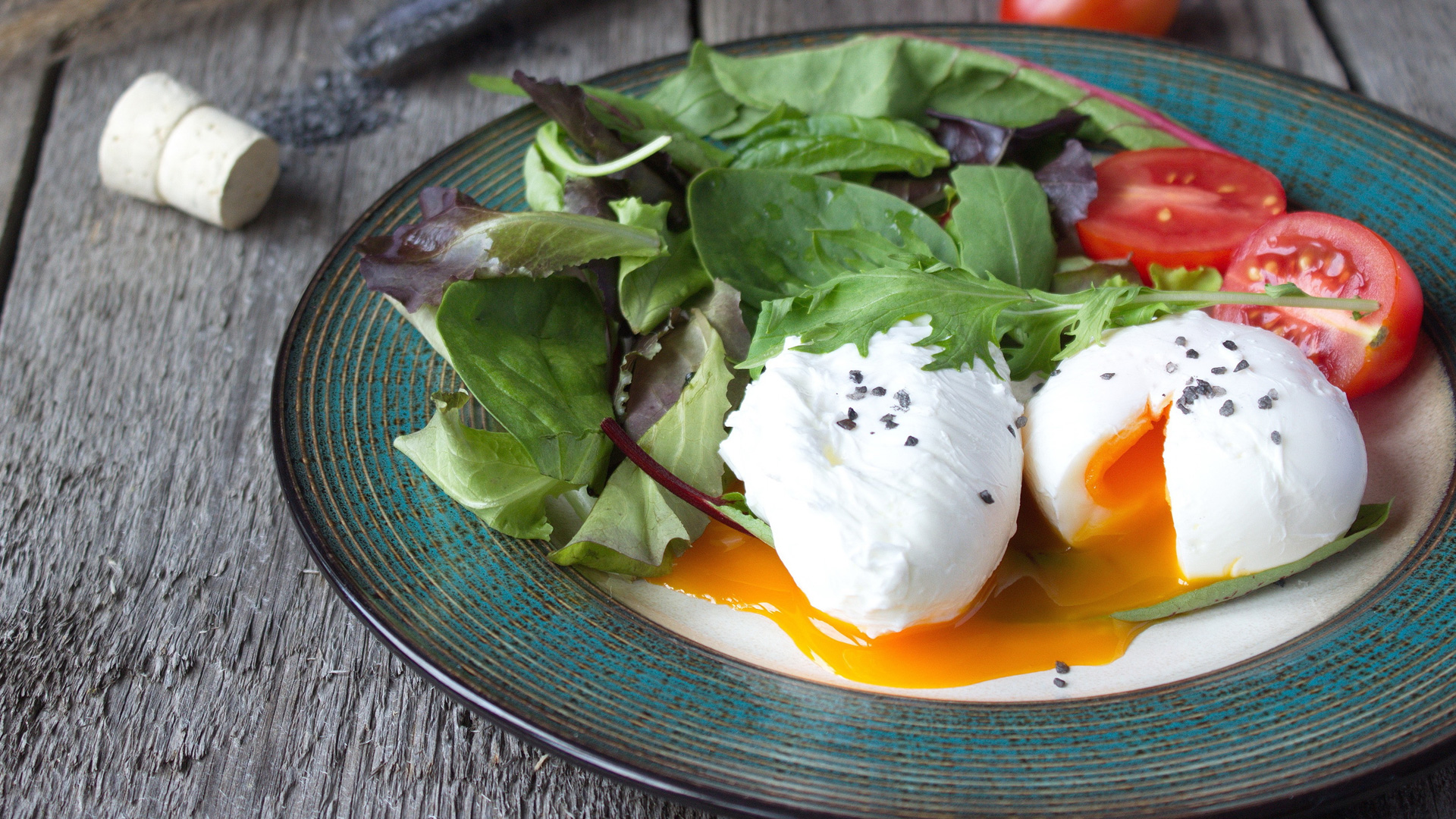 Oeufs pochés sur la plaque avec salade verte et tomates