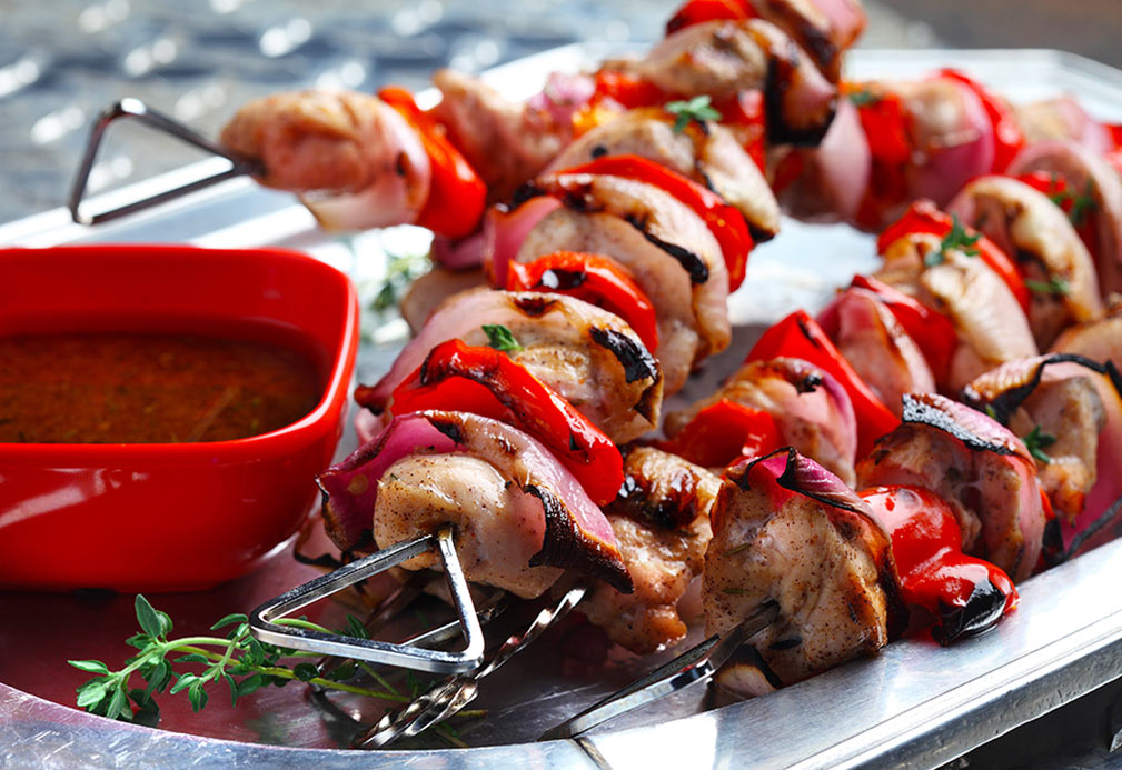 Brochettes de poulet et poivrons rouges grillés sur la plaque avec la marinade