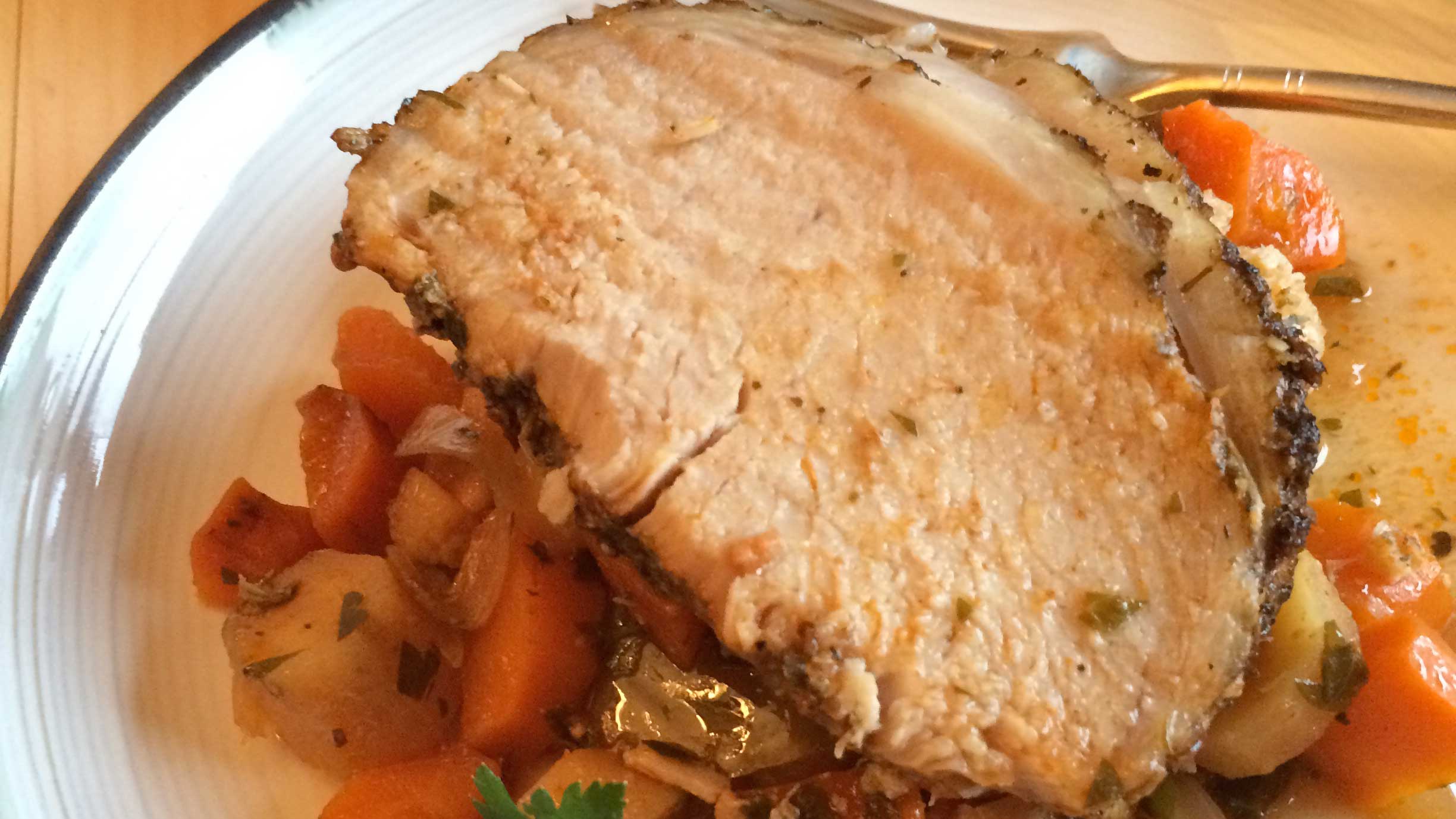 Mijoteuse rôti de porc et des légumes sur une assiette blanche avec une fourchette