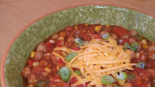 Chili végétarien dans un bol vert avec du fromage râpé