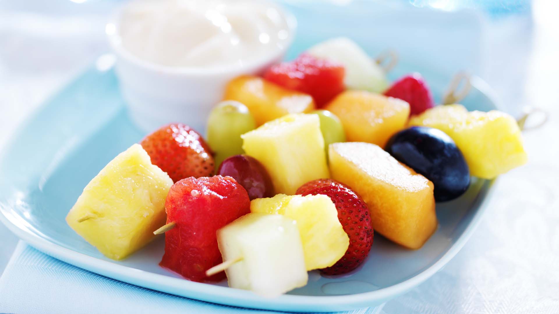 Brochettes de fruits sur une assiette bleue