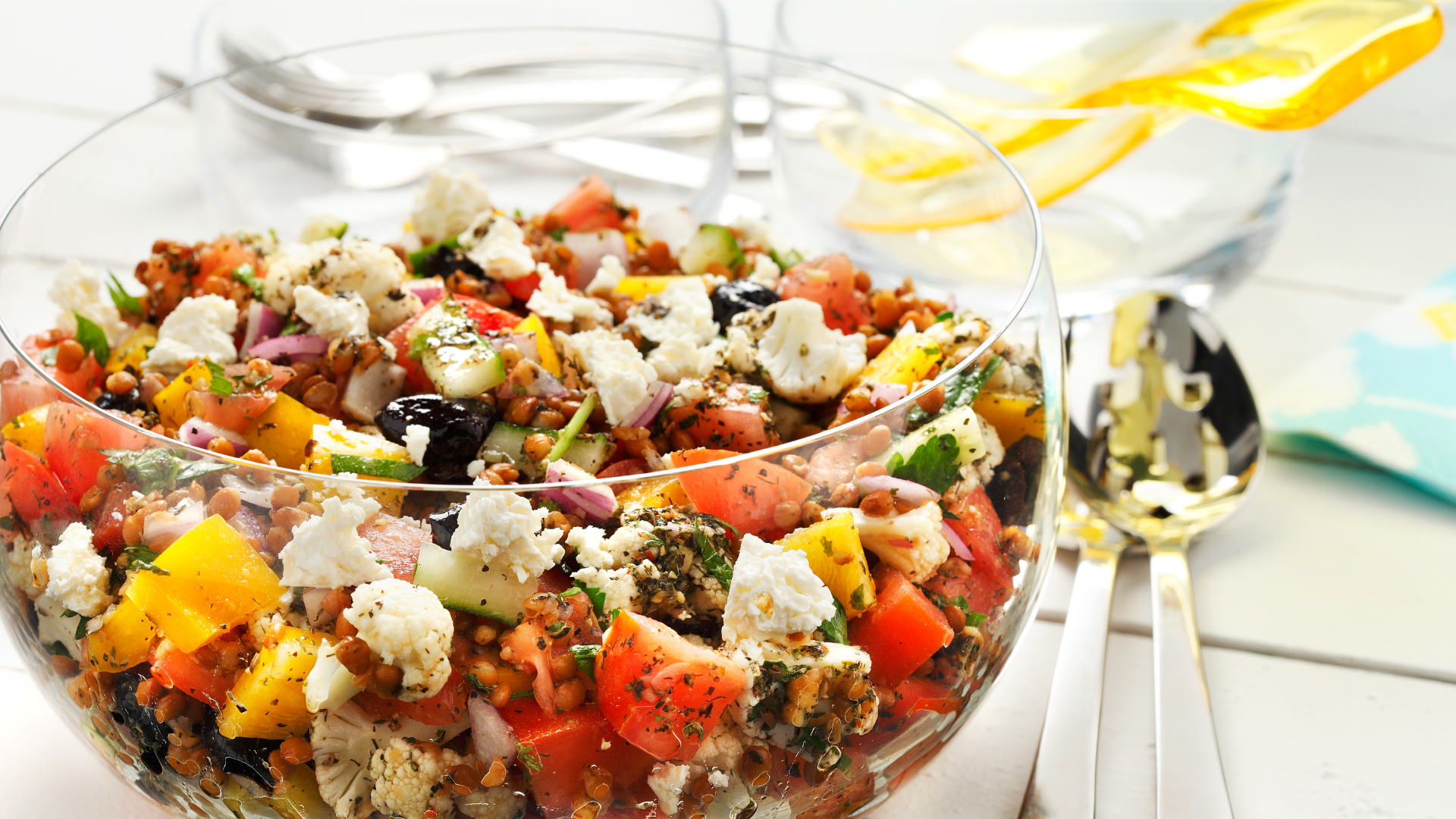 Salade grecque aux lentilles dans un bol transparent avec des ustensiles