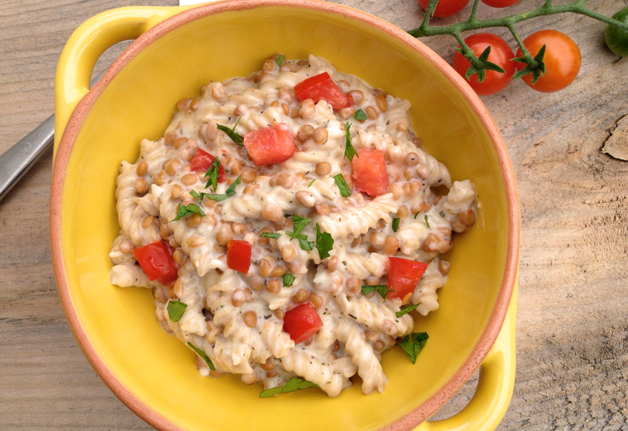 Macaroni au fromage et lentilles dans un bol jaune, garni de tomates en dés et de persil