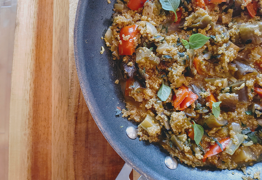Une casserole de quinoa, poivrons rouges et aubergines, garnie d’herbes fraîches