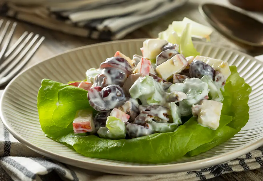 Salade Waldorf garnie de pommes et de petits fruits sur un lit de laitue dans une assiette