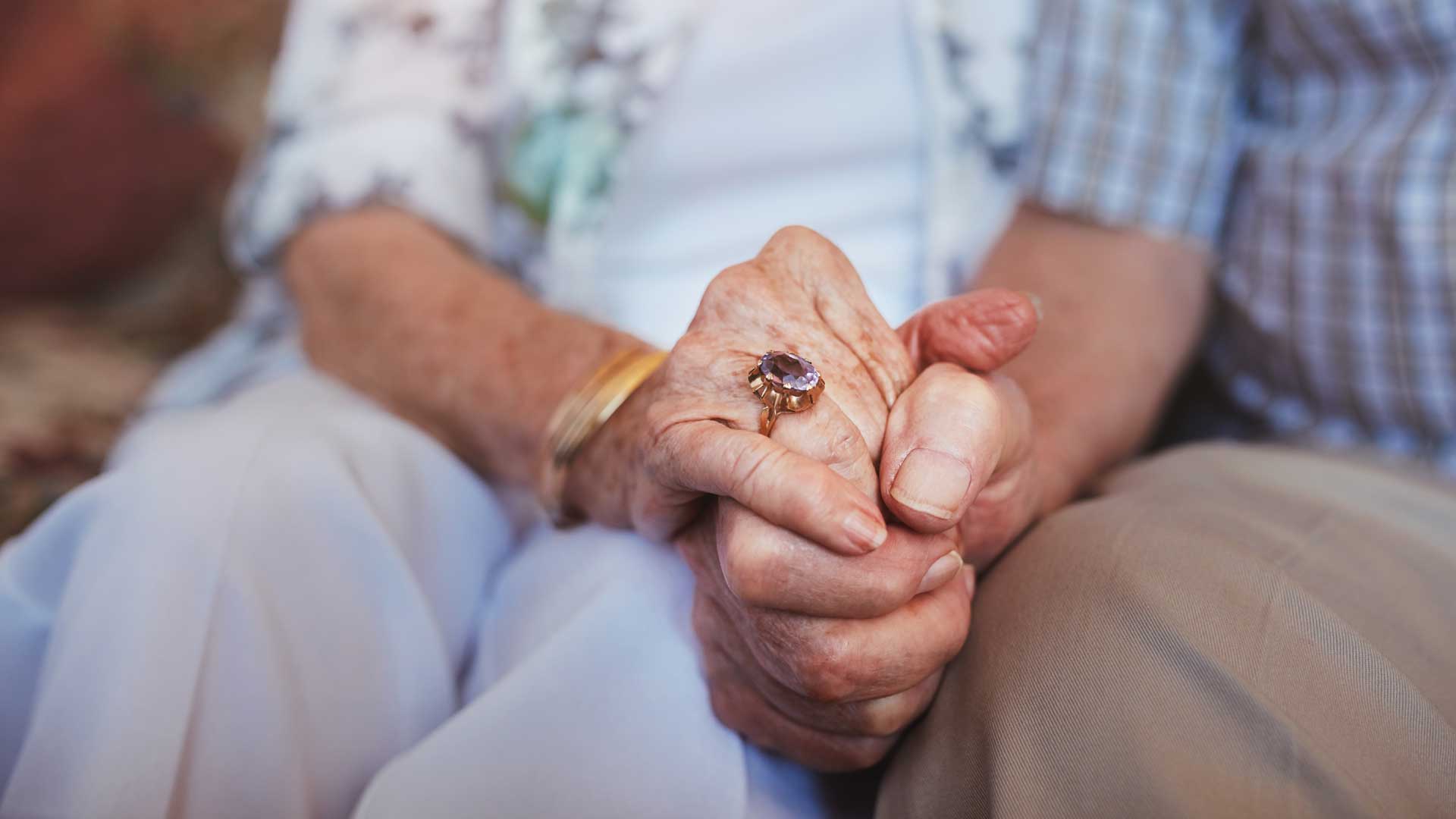 tir tondu couple de personnes âgées tenant la main alors qu'il était assis ensemble à la maison