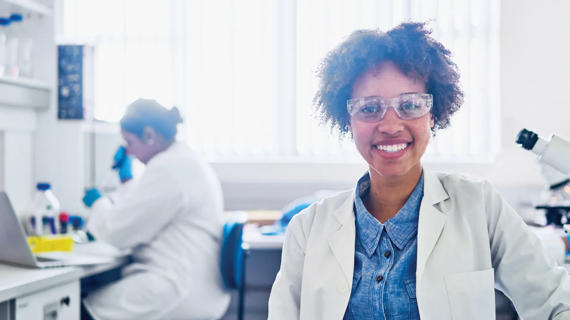 Un chercheur de laboratoire sourit à la caméra tout en tenant une tablette.