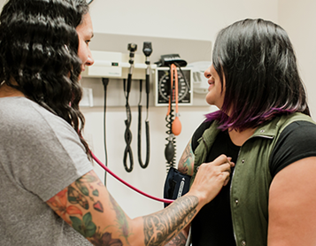 Une femme écoute le cœur d’une autre femme à l’aide d’un stéthoscope dans une clinique de soins pour Autochtones.